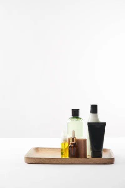 Wooden tray with various cosmetic containers and soap on white surface — Stock Photo