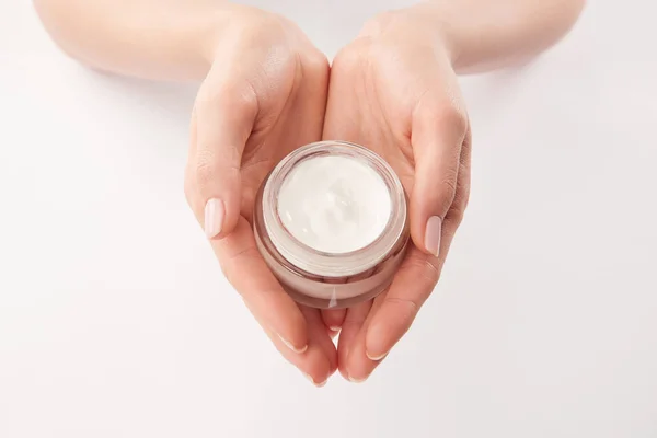 Partial view of woman applying cosmetic cream on white background — Stock Photo