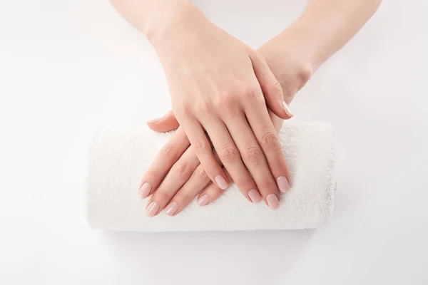 Teilweise Ansicht der weiblichen Hände auf Frottee gerollt Handtuch auf weißem Hintergrund — Stockfoto