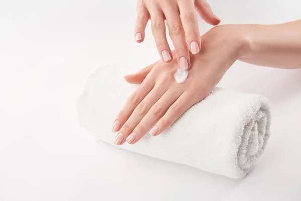 Partial view of woman applying cosmetic cream on white background — Stock Photo