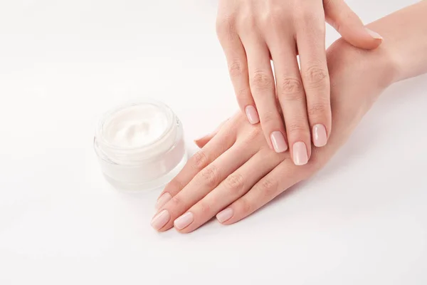 Vista parcial de la mujer aplicando crema cosmética sobre fondo blanco - foto de stock