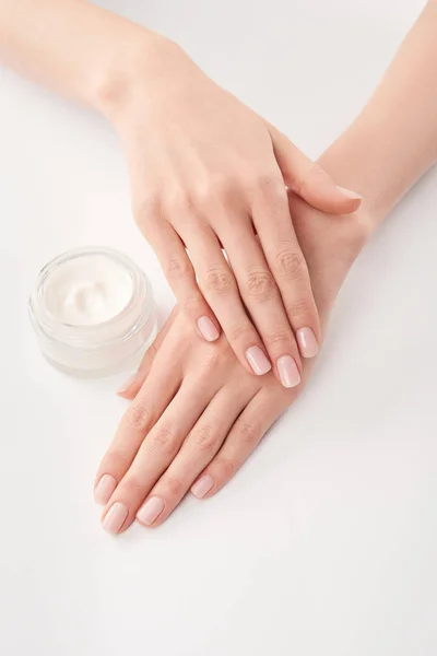 Vista parcial de la mujer aplicando crema cosmética sobre fondo blanco - foto de stock