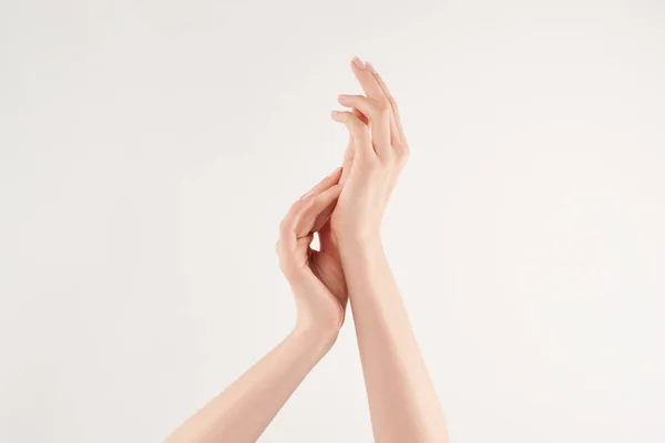 Vista parcial de la mujer aplicando crema cosmética sobre fondo blanco - foto de stock