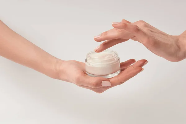 Partial view of woman applying cosmetic cream on white background — Stock Photo