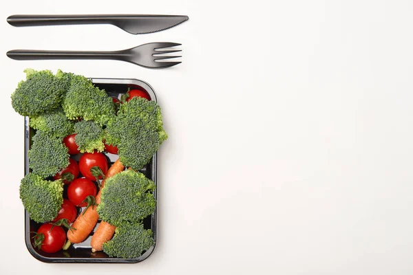Draufsicht auf Schüssel mit Gemüse und Besteck auf weißem Hintergrund — Stockfoto