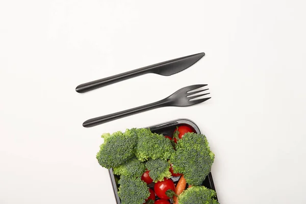 Ansicht von schwarzem Besteck und Gemüse in Schüssel isoliert auf weiß — Stockfoto
