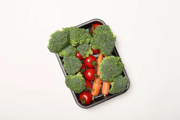 Top view of organic vegetables in black bowl on white background — Stock Photo