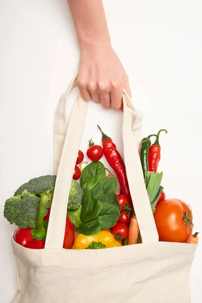 Vista ritagliata della donna che tiene la borsa ecologica con verdure su sfondo bianco — Foto stock