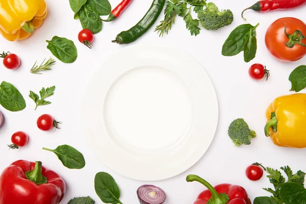 Acostado plano con plato y verduras naturales sobre fondo blanco - foto de stock