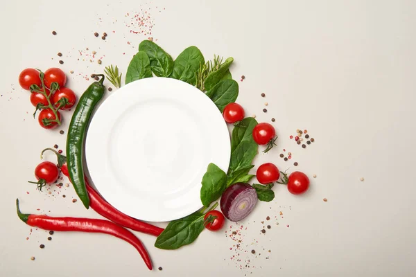 Top view of white plate, vegetables and spices on grey background — Stock Photo