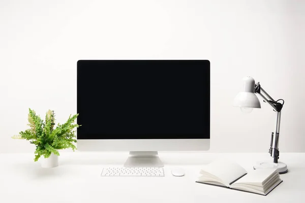 Lugar de trabajo con lámpara, planta verde y computadora de escritorio con espacio de copia aislado en blanco - foto de stock