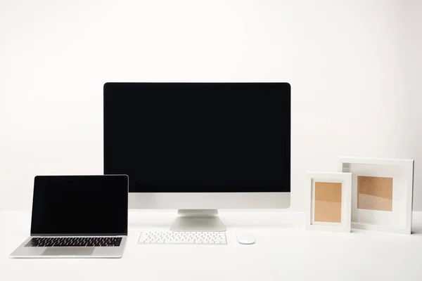 Lieu de travail avec cadres photo, ordinateur de bureau et ordinateur portable avec espace de copie isolé sur blanc — Photo de stock