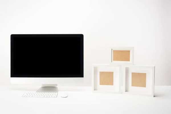 Lugar de trabajo con marcos de fotos y computadora de escritorio con espacio de copia aislado en blanco - foto de stock