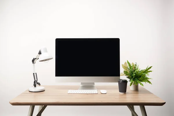 Lugar de trabajo con café para llevar, lámpara, planta verde y computadora de escritorio con espacio de copia aislado en blanco — Stock Photo