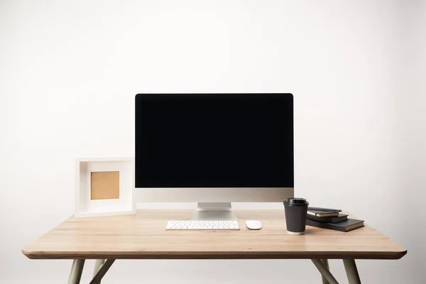 Lugar de trabajo con café para llevar, cuadernos, marco de fotos y computadora de escritorio con espacio de copia aislado en blanco - foto de stock