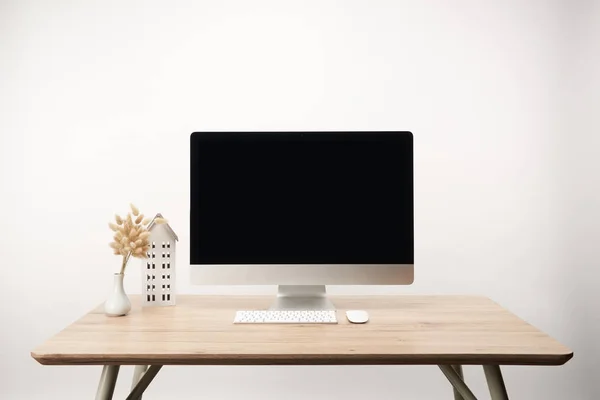 Lugar de trabajo con modelo de casa, flores secas y computadora de escritorio con espacio de copia aislado en blanco - foto de stock