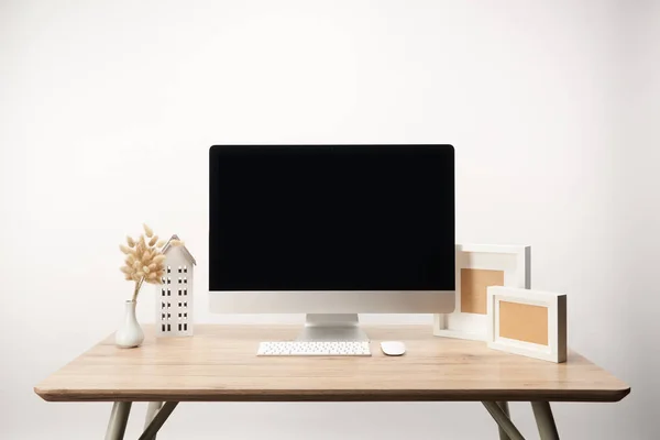 Lugar de trabajo con marcos de fotos, flores secas y computadora de escritorio con espacio de copia aislado en blanco - foto de stock