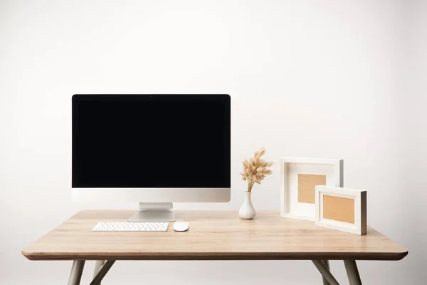 Local de trabalho com molduras para fotos, flores secas e computador desktop com espaço de cópia isolado em branco — Fotografia de Stock