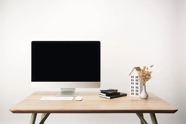 Lugar de trabajo con flores secas, modelo de casa, cuadernos y computadora de escritorio con espacio de copia aislado en blanco — Stock Photo
