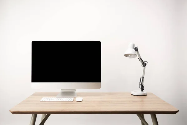 Lugar de trabajo con lámpara y ordenador de sobremesa con espacio de copia aislado en blanco - foto de stock