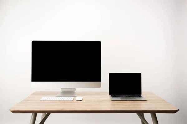 Lugar de trabajo con ordenador de sobremesa y portátil con espacio de copia en mesa de madera aislada en blanco - foto de stock