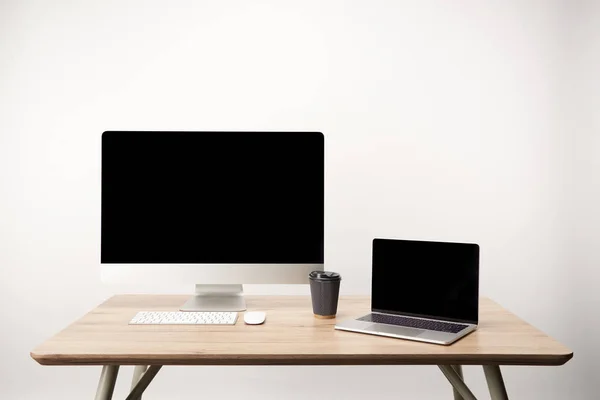 Lugar de trabajo con café para llevar, computadora de escritorio y computadora portátil con espacio de copia aislado en blanco - foto de stock