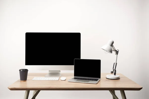 Lugar de trabajo con lámpara, café para llevar, computadora de escritorio y computadora portátil con espacio de copia aislado en blanco — Stock Photo