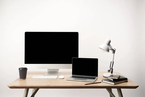 Workplace with lamp, coffee to go, notebooks, desktop computer and laptop with copy space isolated on white — Stock Photo