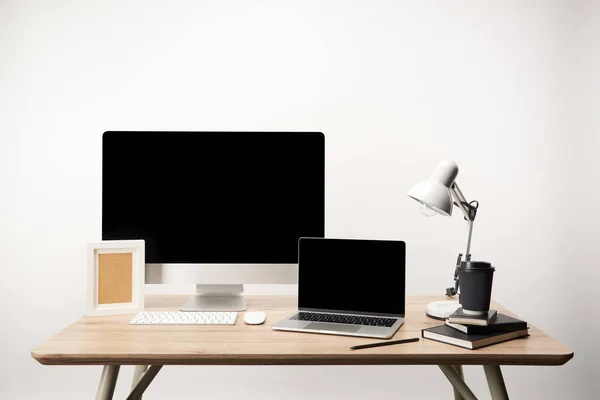 Lugar de trabajo con marco de fotos, café para llevar, cuadernos, computadora de escritorio y computadora portátil con espacio de copia aislado en blanco - foto de stock
