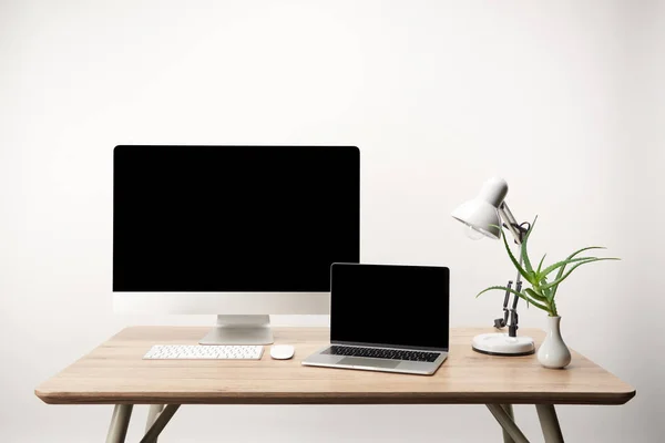 Lugar de trabajo con lámpara, ordenador de sobremesa y portátil con espacio de copia aislado en blanco - foto de stock