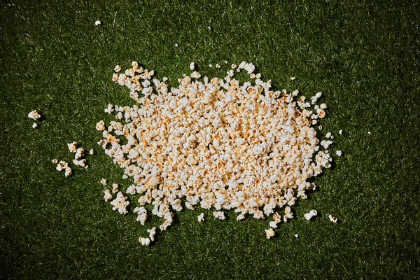 Top view of tasty popcorn lying on green grass — Stock Photo