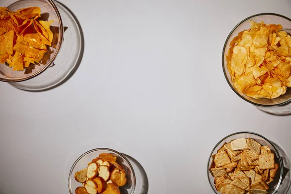 Top view of delecious snacks in bowls on white background — Stock Photo