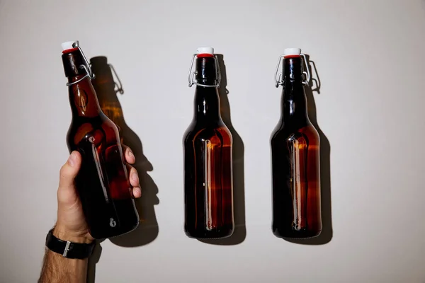 Vista recortada del hombre sosteniendo la botella con cerveza sobre fondo blanco - foto de stock