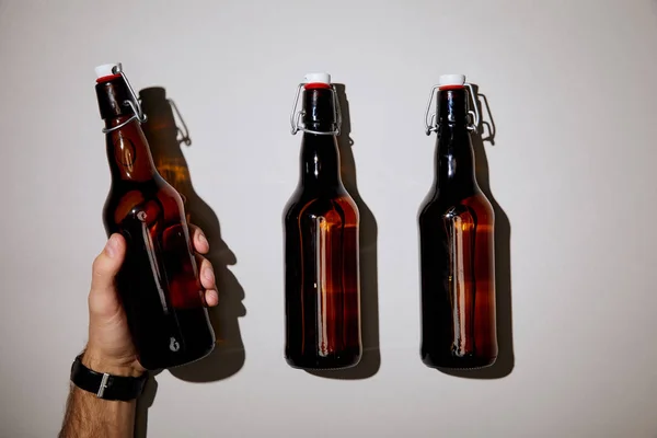 Vue recadrée de l'homme tenant bouteille avec de la bière sur fond blanc — Photo de stock