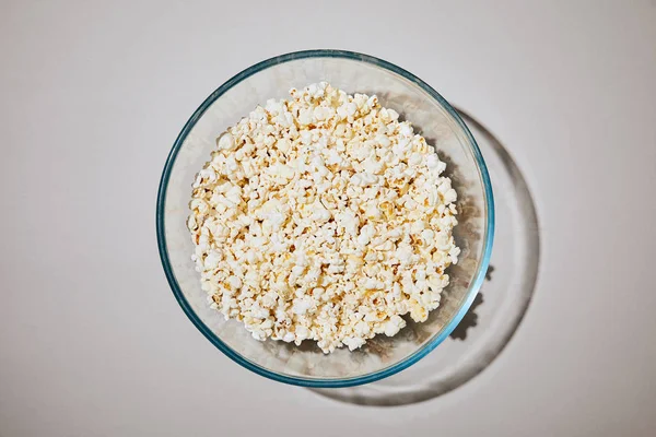 Vista dall'alto di gustosi popcorn in ciotola su sfondo bianco — Foto stock