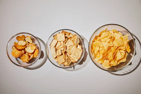 Top view of salty snacks in glass bowl on white background — Stock Photo