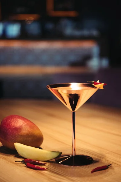 Alcoholic cocktail in metal glass decorated with chili pepper, nacho chip and mango on wooden table — Stock Photo