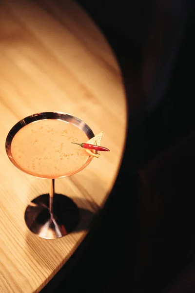 Cocktail alcoolisé en verre métallique décoré de piment et de copeaux de nacho sur table en bois — Photo de stock