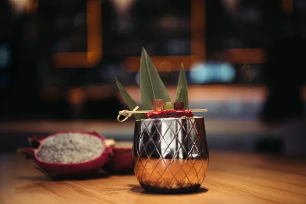 Enfoque selectivo de delicioso cóctel alcohólico tropical decorado con fruta de dragón sobre fondo oscuro - foto de stock