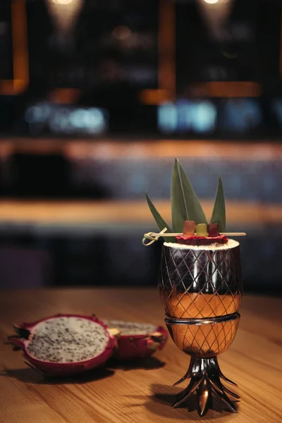 Enfoque selectivo de delicioso cóctel alcohólico tropical decorado con fruta de dragón sobre fondo oscuro - foto de stock