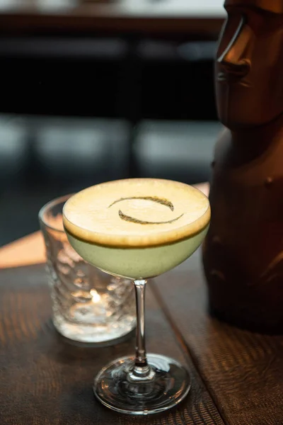 Foco selectivo de delicioso cóctel alcohólico con espuma sobre mesa de madera en bar - foto de stock