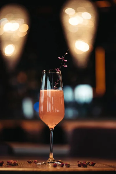 Selective focus of pink alcoholic cocktail decorated with dry flowers on dark background — Stock Photo