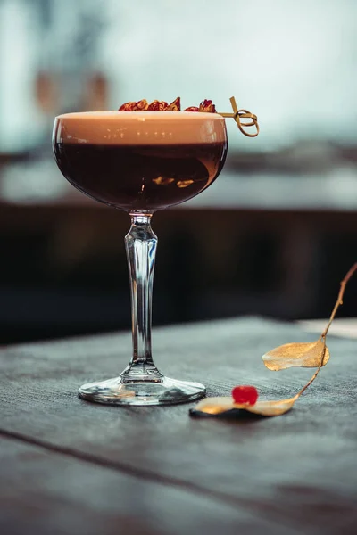 Selektiver Fokus eines alkoholischen Cocktails mit Schaum und trockenen Blumen auf dunklem Hintergrund — Stockfoto