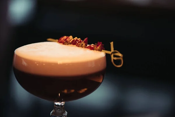 Close up of alcoholic cocktail with foam and dry flowers on dark background with copy space — Stock Photo