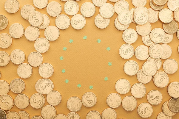 Vista superior de monedas de oro con signos de dólar y círculo de tréboles aislados en naranja, San Patricio concepto de día - foto de stock