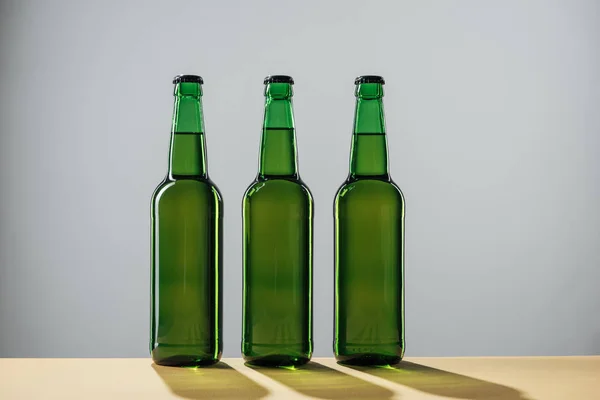 Bottiglie di birra con ombre isolate sul grigio, concetto di giorno di San Patrizio — Foto stock