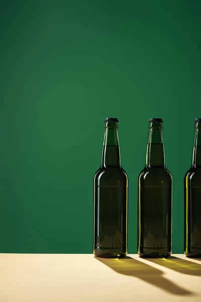 Bouteilles de bière avec ombres et espace de copie isolé sur vert, concept st patrick jour — Photo de stock