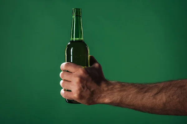 Vue recadrée de l'homme tenant bouteille de bière isolé sur vert, concept st patrick jour — Photo de stock