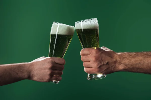 Cropped view of men clinking  glasses of beer isolated on green, st patrick day concept — Stock Photo