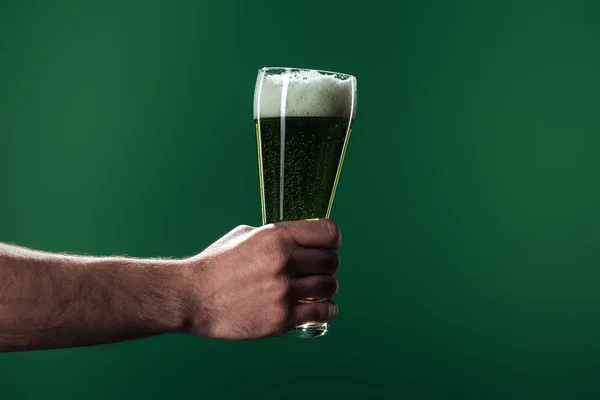 Partial view of man holding glasses of beer with foam isolated on green, st patrick day concept — Stock Photo